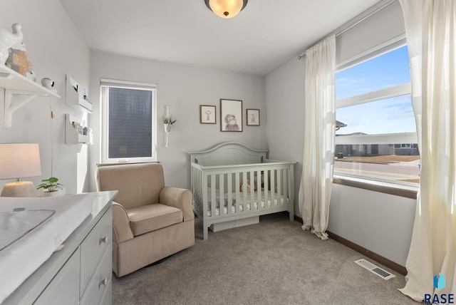 bedroom featuring visible vents, baseboards, light colored carpet, and a crib