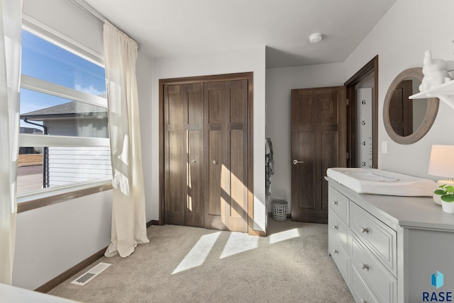 bedroom featuring baseboards, visible vents, light carpet, and a closet