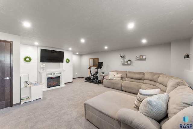 carpeted living area featuring a glass covered fireplace, recessed lighting, a textured ceiling, and baseboards