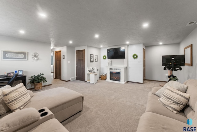 living area with a textured ceiling, recessed lighting, visible vents, and light carpet