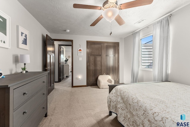 bedroom featuring a ceiling fan, light colored carpet, visible vents, and a textured ceiling