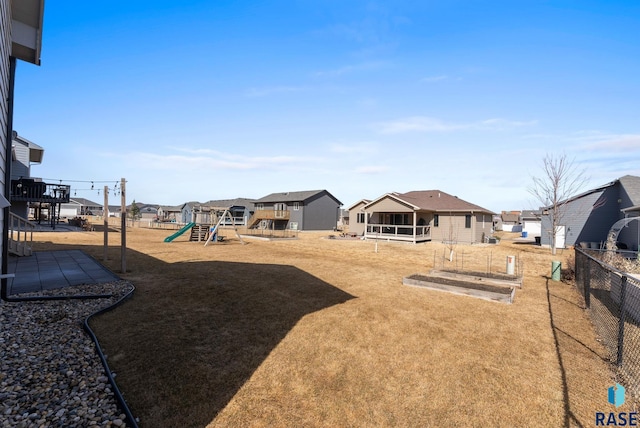 view of yard featuring a residential view, playground community, and fence