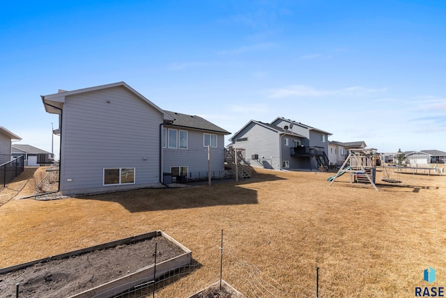 back of house with fence, a garden, a yard, a playground, and a residential view