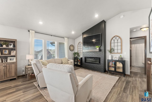 living room featuring wood finished floors, recessed lighting, a fireplace, baseboards, and vaulted ceiling