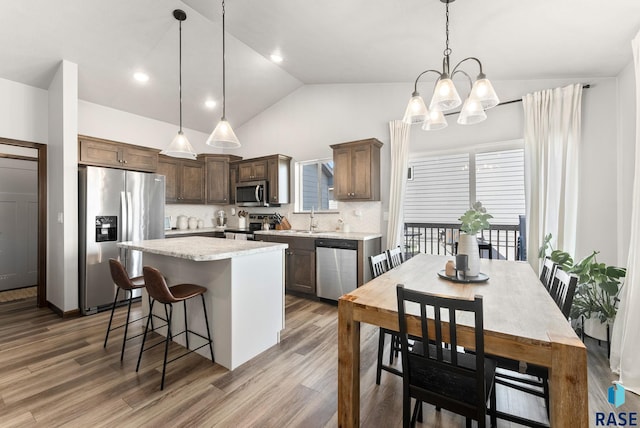 kitchen with a sink, backsplash, a kitchen island, wood finished floors, and stainless steel appliances