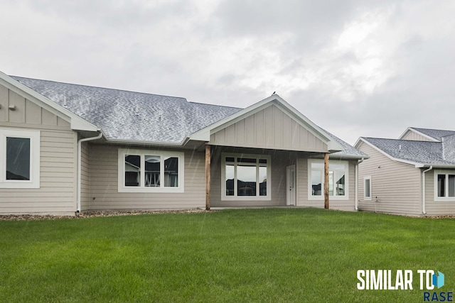 rear view of property featuring a yard, board and batten siding, and roof with shingles