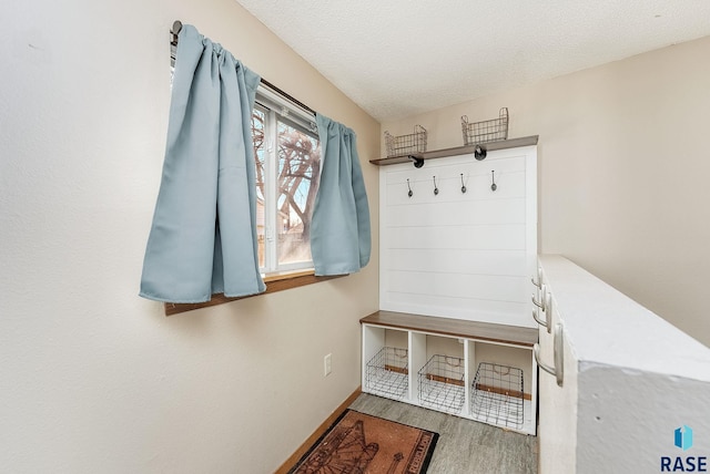 mudroom with baseboards, a textured ceiling, and wood finished floors