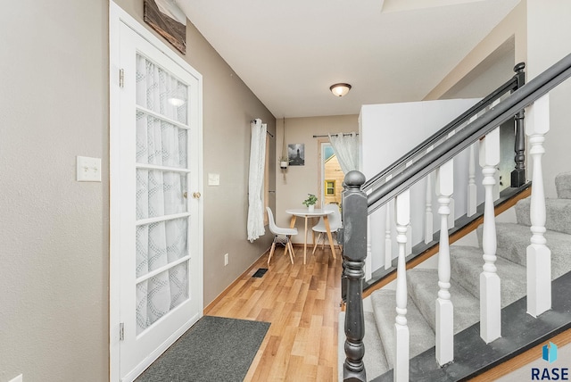 foyer entrance featuring stairs, baseboards, and wood finished floors