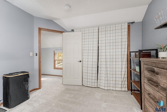 carpeted bedroom with a textured ceiling, baseboards, and vaulted ceiling