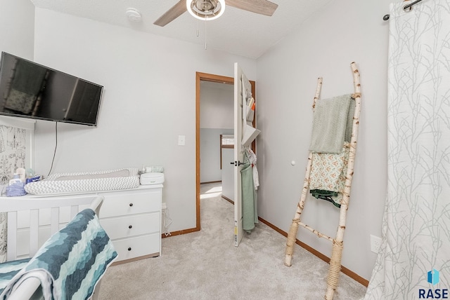 bedroom with a ceiling fan, light colored carpet, baseboards, and a textured ceiling