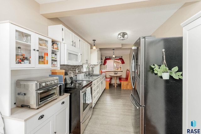 kitchen with backsplash, a toaster, appliances with stainless steel finishes, white cabinetry, and a sink