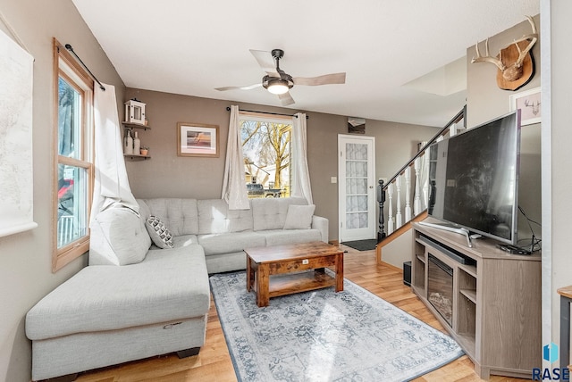 living area with a ceiling fan, stairway, a healthy amount of sunlight, and light wood-type flooring