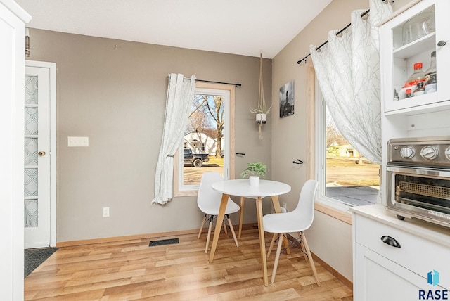 dining area featuring visible vents, baseboards, and light wood finished floors