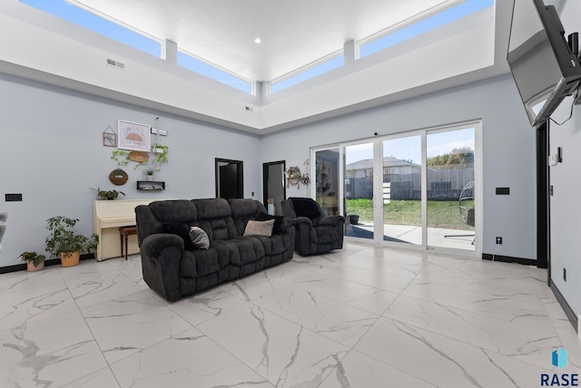 living area with a towering ceiling, baseboards, visible vents, and marble finish floor