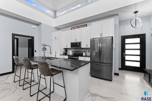 kitchen with marble finish floor, a sink, stainless steel appliances, a breakfast bar area, and white cabinets