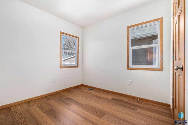 unfurnished room featuring visible vents, baseboards, and wood finished floors