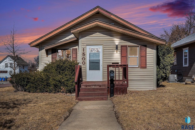 bungalow-style home with cooling unit and a front lawn