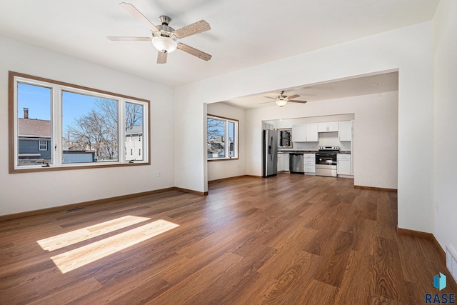 unfurnished living room with dark wood-style floors, ceiling fan, and baseboards