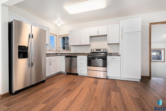 kitchen featuring dark countertops, dark wood finished floors, appliances with stainless steel finishes, and white cabinets