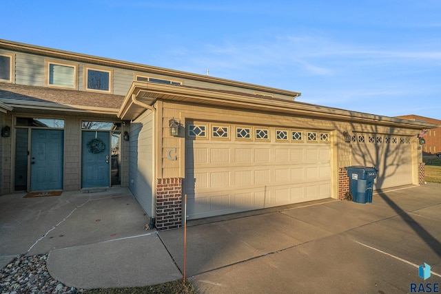 view of front of property featuring an attached garage, brick siding, and driveway