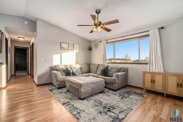 living room with baseboards, a ceiling fan, light wood-type flooring, and lofted ceiling