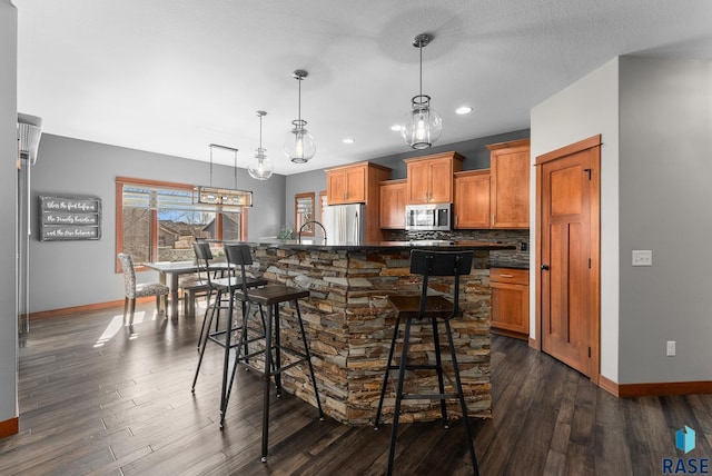 kitchen with dark wood-style floors, brown cabinetry, appliances with stainless steel finishes, dark countertops, and tasteful backsplash