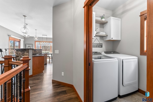 washroom featuring baseboards, cabinet space, dark wood finished floors, and washing machine and clothes dryer