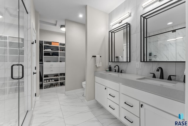 full bath featuring a walk in closet, a stall shower, marble finish floor, and a sink