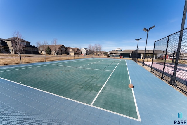 view of tennis court featuring a residential view, community basketball court, and fence