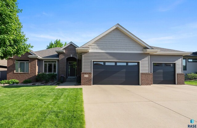 8709 E Palametto St, Sioux Falls, SD 57110 - view of front facade featuring a garage, brick siding, driveway, and a front lawn