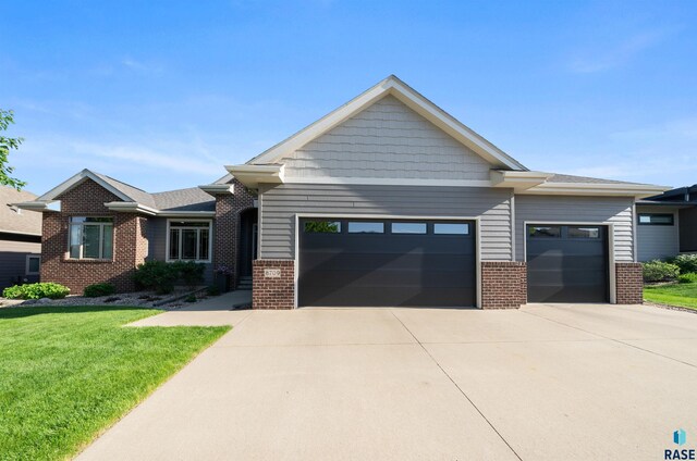 8709 E Palametto St, Sioux Falls, SD 57110 - view of front of property with brick siding, an attached garage, driveway, and a front lawn
