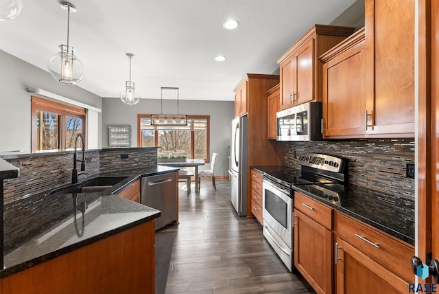 kitchen with brown cabinets, a sink, backsplash, appliances with stainless steel finishes, and a healthy amount of sunlight