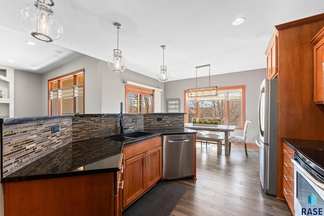 kitchen featuring brown cabinets, dark wood-type flooring, a sink, tasteful backsplash, and stainless steel appliances