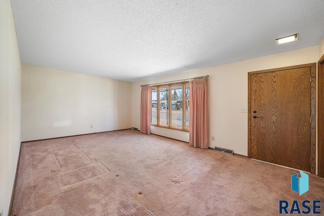 carpeted spare room featuring visible vents and a textured ceiling