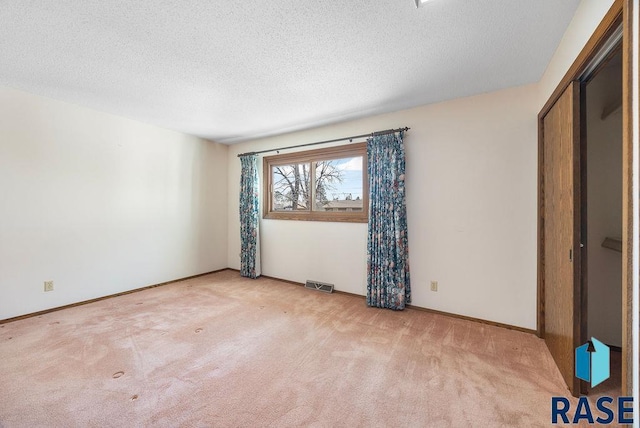 unfurnished bedroom featuring baseboards, carpet flooring, a textured ceiling, and visible vents