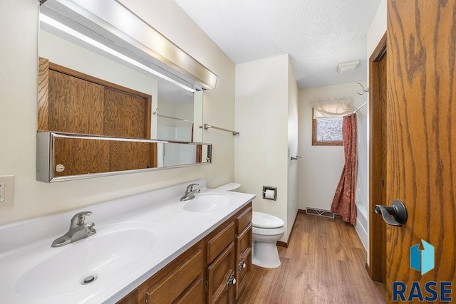 full bath with a textured ceiling, toilet, visible vents, and a sink