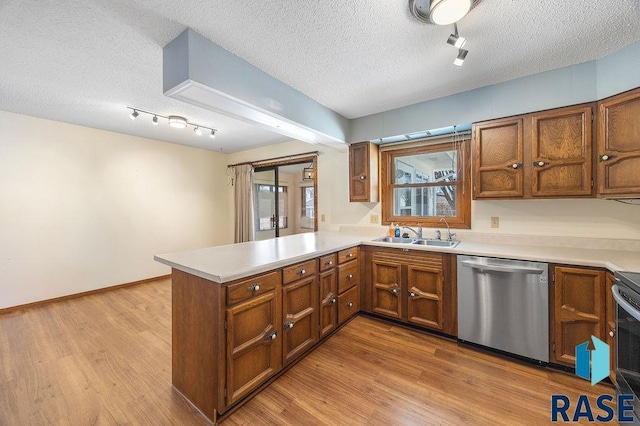 kitchen featuring dishwasher, a peninsula, brown cabinetry, and a sink