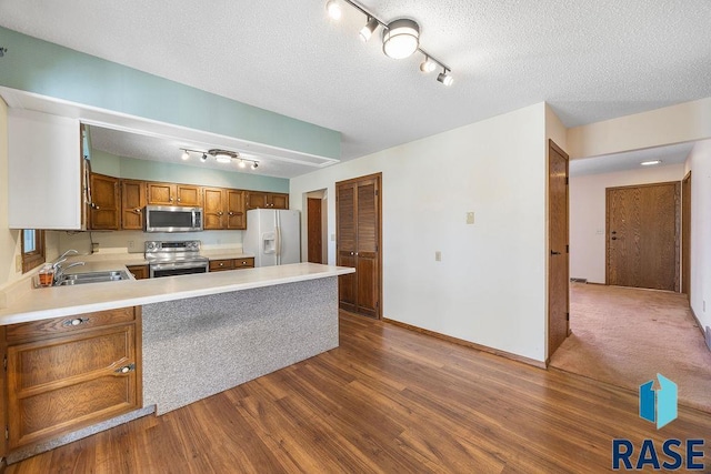 kitchen featuring a sink, appliances with stainless steel finishes, dark wood-style floors, and light countertops