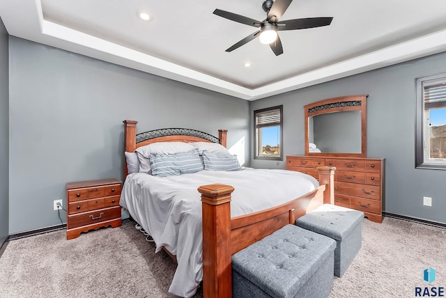 carpeted bedroom featuring a raised ceiling, multiple windows, recessed lighting, and ceiling fan