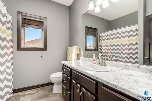 bathroom featuring a shower with curtain, toilet, wood finished floors, baseboards, and vanity