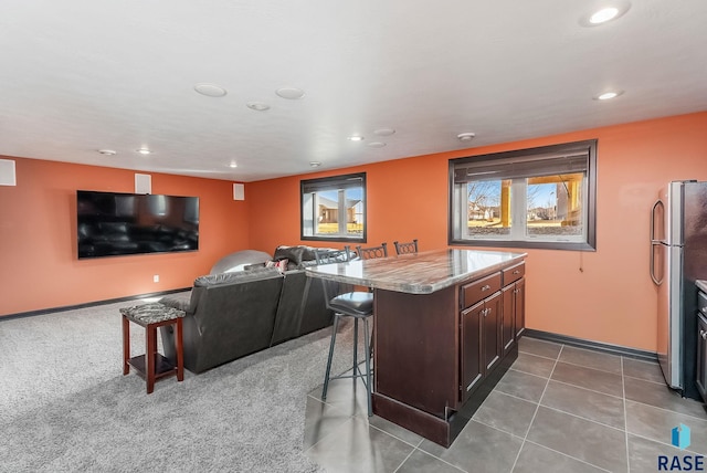 interior space featuring open floor plan, recessed lighting, a kitchen breakfast bar, a peninsula, and freestanding refrigerator