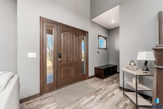 foyer entrance with visible vents, baseboards, and light wood-style floors