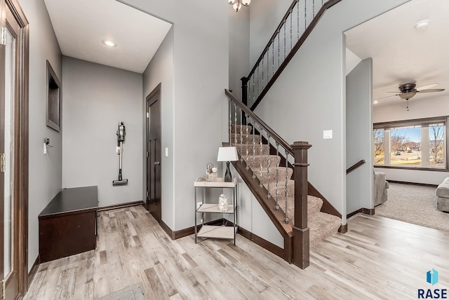 foyer with baseboards, a ceiling fan, wood finished floors, and stairs