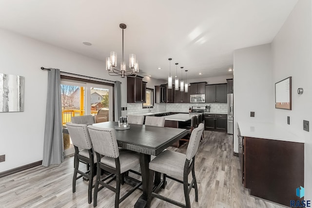 dining room with light wood-style flooring, a notable chandelier, recessed lighting, and baseboards