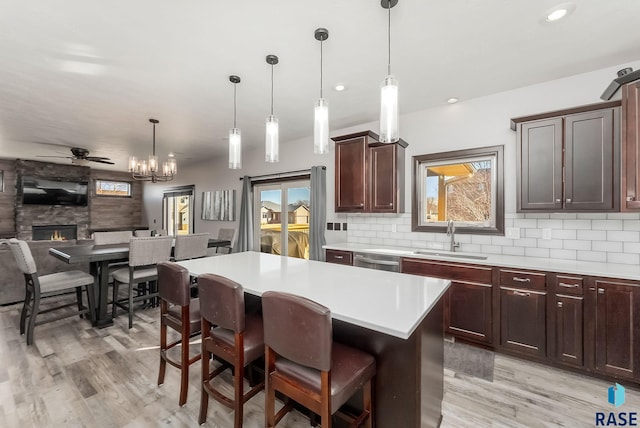 kitchen featuring a sink, decorative backsplash, light countertops, stainless steel dishwasher, and open floor plan