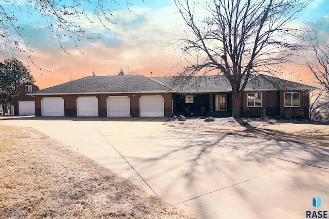 ranch-style house featuring stone siding, concrete driveway, a garage, and a shingled roof