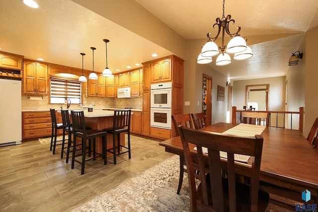 dining area featuring an inviting chandelier, recessed lighting, light wood-type flooring, and a textured ceiling