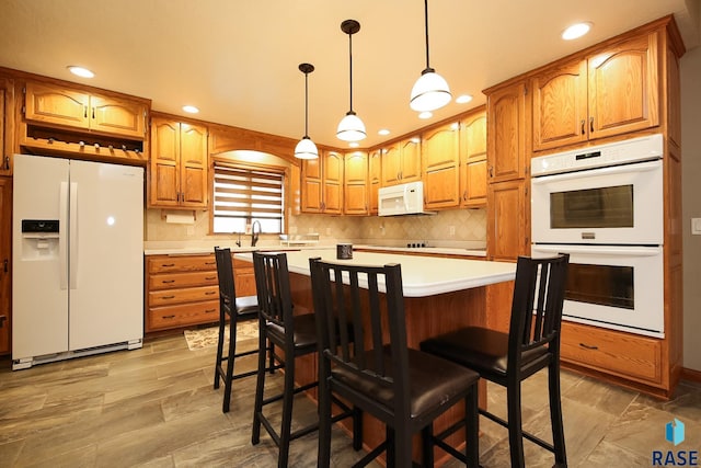 kitchen featuring backsplash, light countertops, hanging light fixtures, brown cabinetry, and white appliances