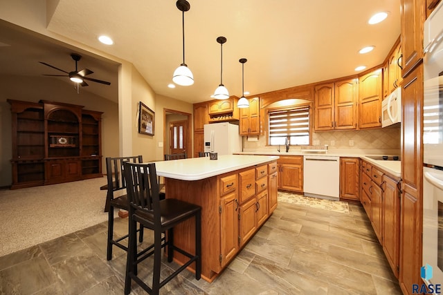 kitchen featuring backsplash, a center island, light countertops, white appliances, and a sink