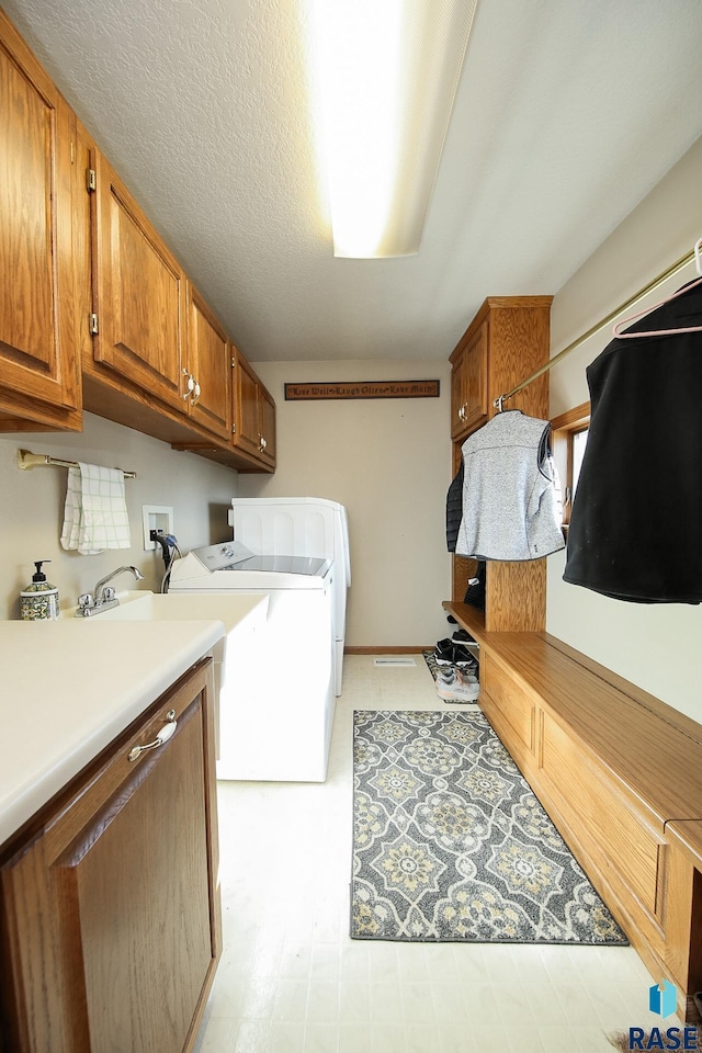 washroom featuring cabinet space, washer and dryer, a textured ceiling, and light floors